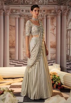 Step into glamour with this exquisite gray sari, crafted from luxurious sequined fabric. The heavy skirt provides a stunning foundation, while the draped pallu is fully embroidered, featuring beautiful long tassels that add a playful touch. The padded blouse ensures a flattering fit, making this ensemble perfect for grand occasions where elegance and sophistication are essential. Embrace the allure of this captivating outfit, designed to make a lasting impression. Diwali Silver Pre-draped Saree With Mirror Work, Silver Embellished Pre-draped Saree, Festive Silver Pre-draped Saree With Unstitched Blouse, Silver Embellished Sharara For Party, Elegant Silver Saree With Mirror Work, Evening Silver Saree With Zari Work, Traditional Silver Festive Dress, Traditional Silver Dress For Festive Occasions, Silver Festive Dress With Sheer Dupatta