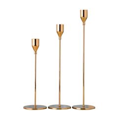 three gold colored candlesticks are standing next to each other on a white background