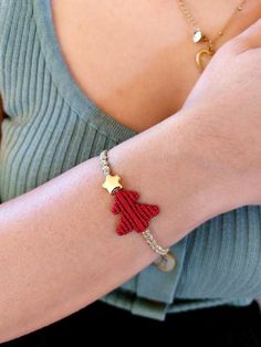 a woman's arm with a red and gold star bracelet on her left wrist