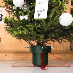 a small christmas tree in a green pot with ornaments hanging from it's sides