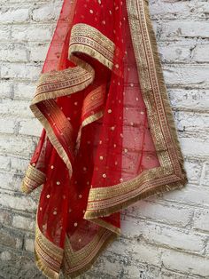 a red and gold sari hanging on a brick wall