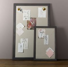 two framed pictures on a wall with papers and magnets attached to the frames,