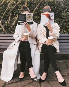 two women sitting on a bench reading books