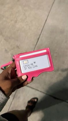 a person holding up a pink card case that says, catch me if you can