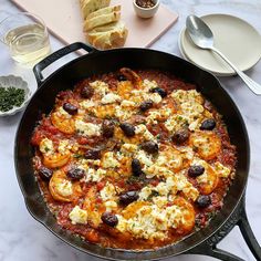 a pan filled with food sitting on top of a table next to plates and utensils