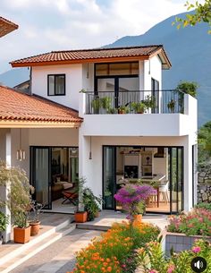 a large white house with lots of flowers in the front yard and balconyes on both sides