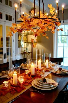 a dining room table is set with candles and fall leaves on the placemats