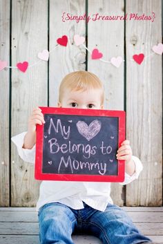 a little boy holding up a chalkboard with the words my belongs to mommy