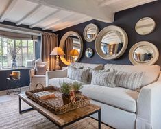 a living room with mirrors on the wall and furniture in front of it's windows