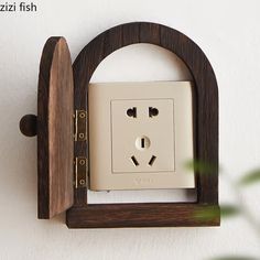 an electrical outlet on the wall with a wooden frame around it and a green plant