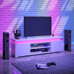 an entertainment center with speakers and a television on it in front of a brick wall