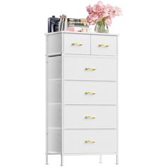 a tall white cabinet with drawers and flowers on top of it, against a white background