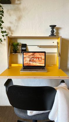 an open laptop computer sitting on top of a wooden desk next to a black chair