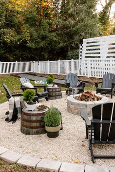 an outdoor fire pit surrounded by chairs and tables with trees in the backgroud