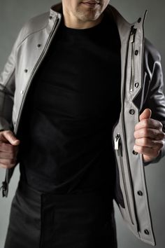 A leather jacket like a concrete slab. The District is inspired by the simple but refined beauty of Brutalist architecture. Clean, stark lines form the body panels and collar, while a hemispherical articulated raglan sleeve provides mobility in a close silhouette. Two front pockets are sealed with magnets, while two large zippered internal pockets offer larger, secure storage. A zippered chest pocket is accessible while the jacket remains zipped shut to provide accessible, discrete, and secure s Modern Fitted Leather Biker Jacket, Modern Fitted Leather Jacket With Padded Collar, Modern Leather Biker Jacket With Long Sleeves, Modern Leather Jacket With Padded Collar, Modern Leather Jacket With Padded Collar For Business, Modern Leather Jacket For Work, Modern Business Outerwear, Gray Leather Long Sleeve Outerwear, Modern Leather Jacket For Business