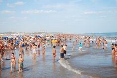 many people are on the beach and in the water at the same time as they walk