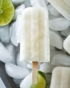 a popsicle with limes and ice cubes in the background on a stick