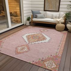 a pink area rug sitting on top of a wooden floor next to a white couch