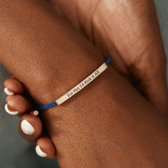 a woman's hand with a blue string bracelet that says, be fearless