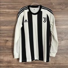 a black and white soccer jersey hanging on a wooden wall next to a hanger