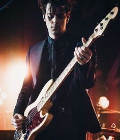 a man in a tuxedo playing an electric guitar on stage at a concert