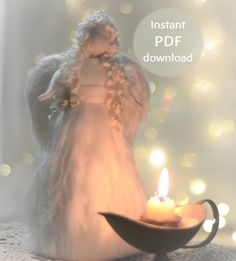 an angel figurine holding a lit candle on top of a plate with lights in the background