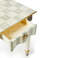 a white and gold table with a drawer on the top that has a checkerboard design