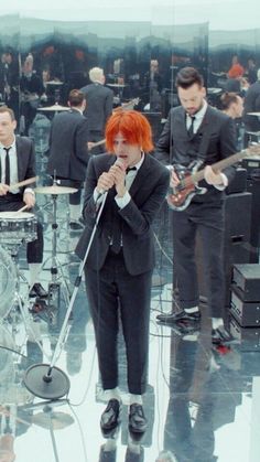 a woman with red hair is singing into a microphone while other people are playing instruments in the background