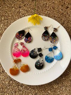 a white plate topped with lots of different colored earrings