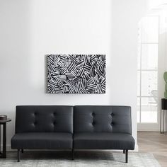 a black and white couch sitting in a living room next to a painting on the wall