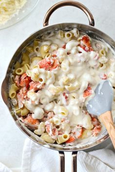 a skillet filled with macaroni and cheese on top of a white table