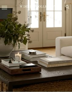 a coffee table with two books and a candle on it in front of a door