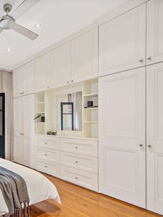 a bedroom with white cabinets and a bed in the middle is shown, along with a ceiling fan