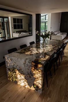 a dining room table with chairs and a large mirror on the wall in front of it