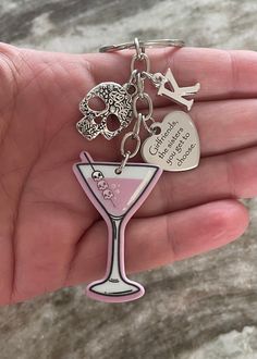 a hand holding a keychain that has a drink in it and two charms attached to it