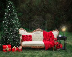 a white couch with red pillows and christmas presents on it in front of a christmas tree