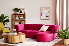 a living room with pink couches and green chairs in the corner, along with potted plants