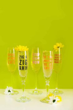 five wine glasses with different designs on them and flowers in the bottom one is yellow