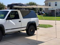 a white truck parked in front of a house with a tent attached to the roof