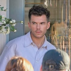 a man standing in front of a store window with people looking at him from behind