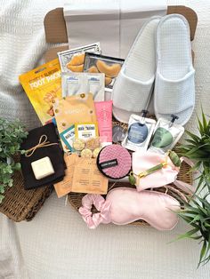 a basket filled with lots of items on top of a white bed next to a potted plant