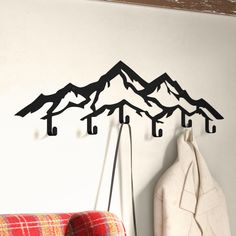 there is a coat rack on the wall with hooks in front of it and mountains