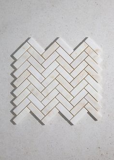 a white marble herringbone tile pattern on a gray background with some light brown lines