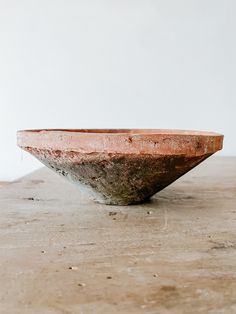 a large bowl sitting on top of a wooden table next to a white wall in the background