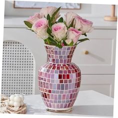 a vase filled with pink roses sitting on top of a white table next to an egg