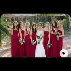 a group of women standing next to each other wearing red dresses and holding bouquets