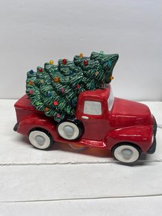 a red truck with a christmas tree on the back is sitting on a white surface