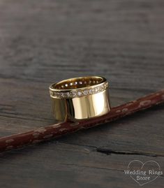 a close up of a gold ring on top of a piece of wood with diamonds