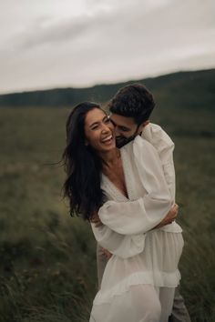 a man and woman hugging in the middle of a field