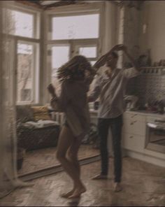 two people standing in a kitchen with one person holding up the other's hair